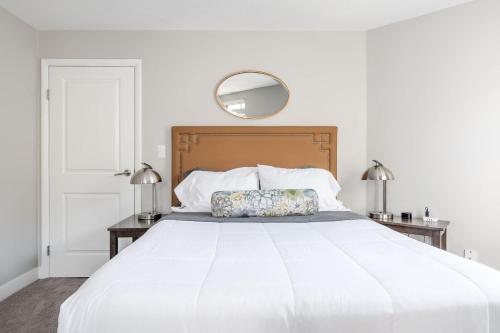 a white bedroom with a white bed with a wooden headboard at Corner view close to Gainsbridge and Lucas Oil in Indianapolis