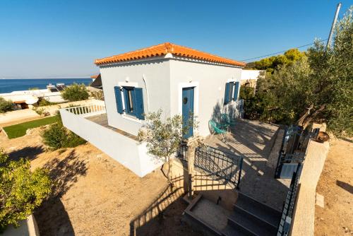 a white house with a blue door and the ocean at The Dona House in Vaia