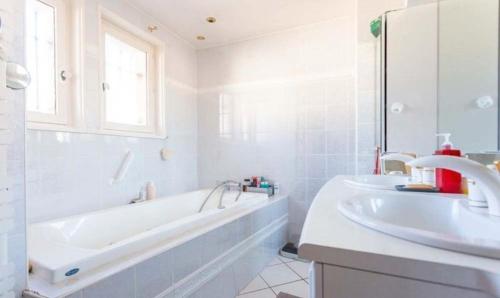 une salle de bain blanche avec une baignoire et un lavabo dans l'établissement Maison cosy avec piscine, à Paray-le-Monial