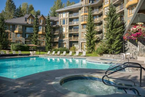 a swimming pool in front of a large apartment building at Renovated 1Bed-1Bath in Village with Pool, Hot Tub, and Sauna in Whistler