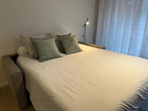 a large white bed with four pillows on it at Studio-be in Nieuwpoort