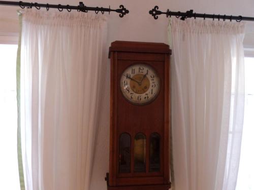 a grandfather clock sitting in front of two windows at Ferienhäusel am Malerweg mit Terrasse in Bad Schandau