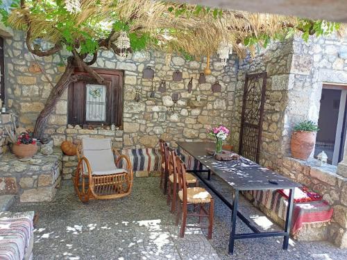 a table and chairs in front of a stone wall at Traditional Creta stone house in serenity village in Vitsiliá