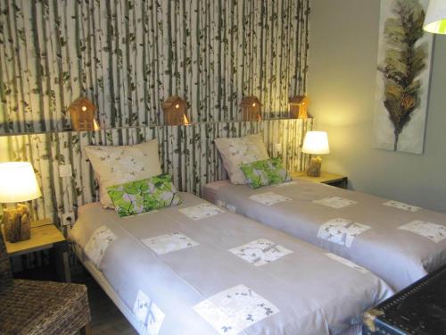 two twin beds in a room with two lamps at Manoir Desnachez in Taupont