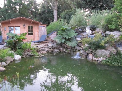 a garden with a pond and a house at Manoir Desnachez in Taupont