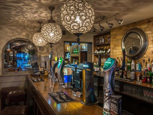 a bar in a pub with a counter with a bartender at The Admiral Rodney Hotel, Horncastle, Lincolnshire - The Coaching Inn Group in Horncastle