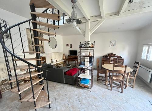 un salon avec un escalier en colimaçon et une table dans l'établissement Maison Colette, à Sainte-Maure
