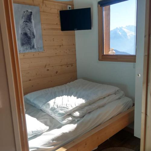 un petit lit dans une chambre avec une fenêtre dans l'établissement Appartement entièrement rénové, vue exceptionnelle, à Huez