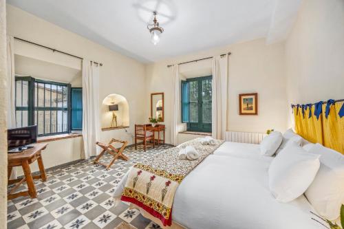 una camera da letto con un grande letto bianco e una scrivania di Molino Fuentesanta ad Aracena
