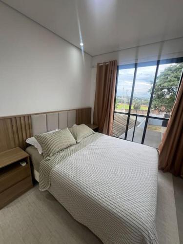 a bedroom with a bed and a large window at Sobrado confortavel e central in Foz do Iguaçu