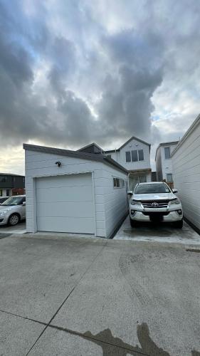 a car parked in a parking lot next to a garage at Stylish New & Cosy 3-Bedroom Entire Home in Auckland, Free Parking - Perfect for Your Next Getaway! in Auckland