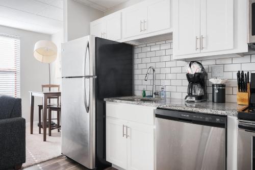 a kitchen with white cabinets and a stainless steel refrigerator at Modern Mass Ave 1BR Apartment with Kitchen in Indianapolis