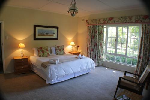 een slaapkamer met een bed en een groot raam bij Cedar Garden in Underberg