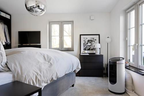 a white bedroom with a bed and a television at Luxury Villa - Private Pool and Lake View in Nacka