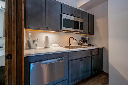 a kitchen with blue cabinets and a sink and a microwave at Cove Creek Lodge 209 Standard Double Queen Room in Oakland