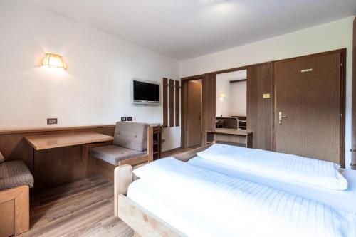 a hotel room with a large bed and a desk at Hotel Zum Löwen - Al Leone in Meltina
