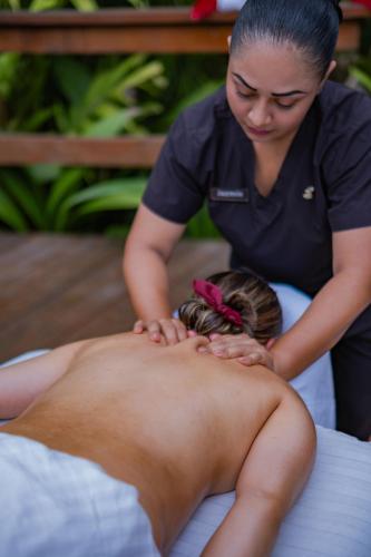a woman getting a massage from a man on a bed at Chachagua Rainforest Hotel & Hot Springs in Fortuna