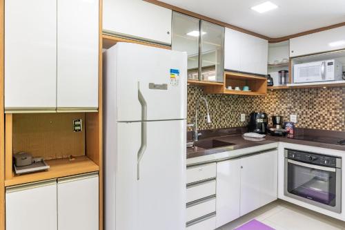 a kitchen with white cabinets and a refrigerator at Flat ou Bangalo Luxo Beach Class Beira Mar Muro Alto in Porto De Galinhas