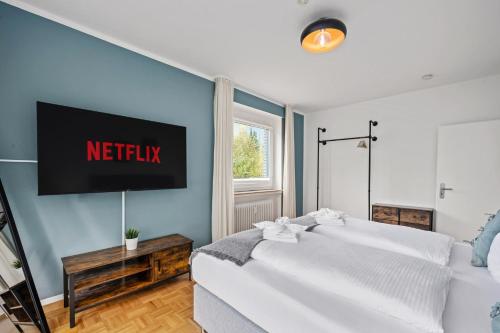 a bedroom with a bed with a television on the wall at Stilvolle Stadtoase, 116 qm, Parkblick, Wassernah, Parkplatz in Wilhelmshaven