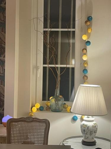 a table with a lamp and a vase on a window at 23 Lesigne in Lisieux