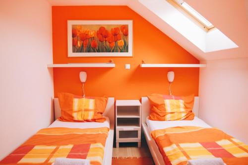 Duas camas num quarto com uma parede laranja em Apartments Sasha em Bled