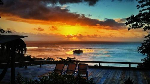 a sunset over the ocean with chairs on a deck at L'Auberge Polynésienne in Tevaitoa
