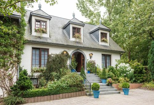 Una casa blanca con escaleras y plantas delante. en Hotel Steineweiher en Saint-Vith