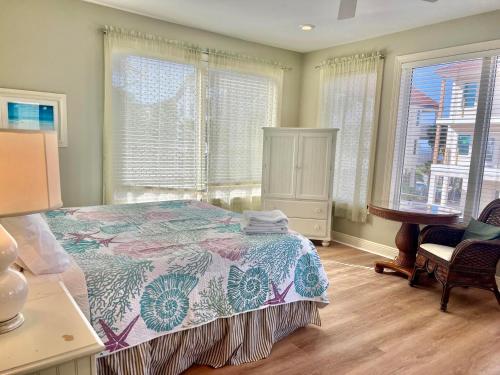 a bedroom with a bed and a desk and windows at Cool Change- Sunset Beach- Beachfront- Pet-Friendly in St. George Island