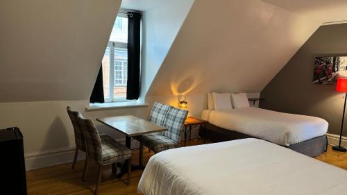 a hotel room with two beds and a table and chairs at E-Hotel Des Grisons - Par Aneyro in Quebec City