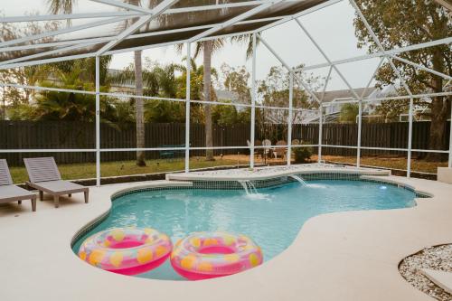 a swimming pool with two inflatables in a house at Luxury Private Pool Villa near Disney with Fire Pit, Game Room & More in Kissimmee
