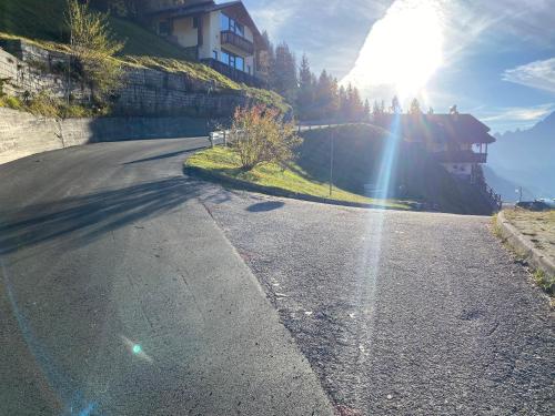 an empty road on a hill with the sun shining at Casa di Sere in Pieve di Livinallongo