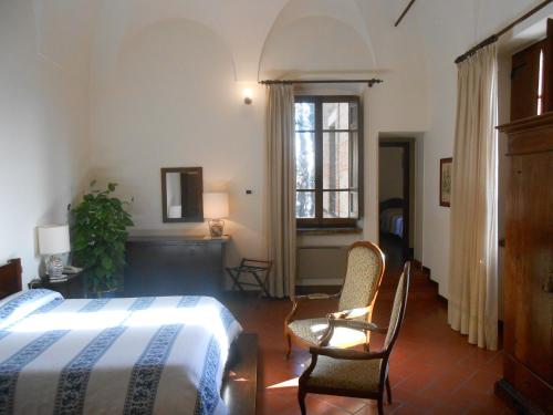 a bedroom with a bed and two chairs and a window at Lo Spedalicchio in Bastia Umbra