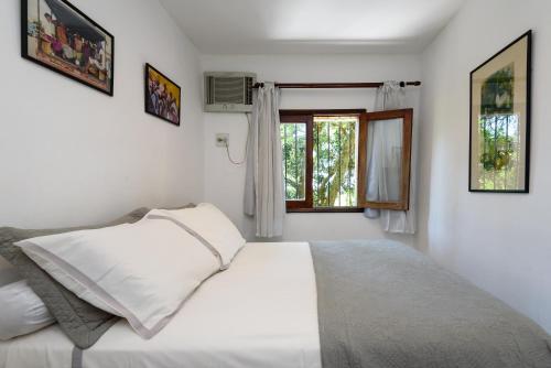 a white bedroom with a bed and a window at Santa Teresa Junto à Natureza in Rio de Janeiro