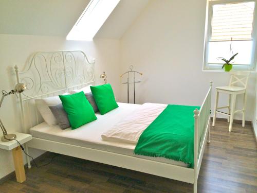 un letto bianco con cuscini verdi in una camera da letto di ferien-wohnen a Mautern an der Donau