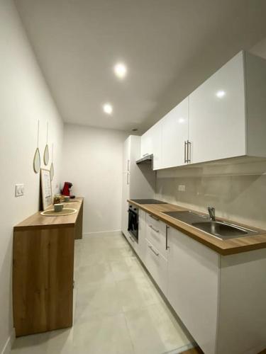 une grande cuisine avec des placards blancs et un évier dans l'établissement T2 Cosy proche Centre Ville, à Bergerac