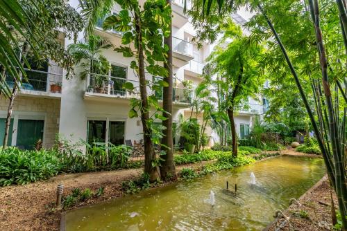 a hotel with a pond in front of a building at Papaya 15 Apartments in Playa del Carmen