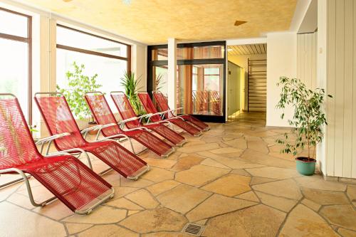a row of red chairs sitting on a patio at BSW Schwarzwaldhotel Baiersbronn in Baiersbronn