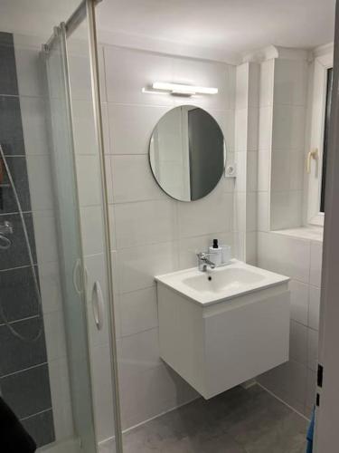 a white bathroom with a sink and a shower at Zahra in Basse-Yutz