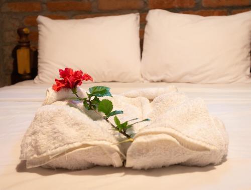 a white towel with a red flower on a bed at Congos Lodge in El Perú