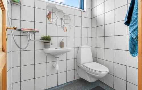 a white tiled bathroom with a toilet and a sink at 3 Bedroom Nice Apartment In Allinge in Allinge