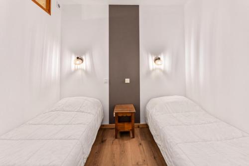 deux lits dans une chambre aux murs blancs dans l'établissement Résidence Les Hauts De Preclaux - Appartement rénové avec terrasse face aux pistes MAE-3431, aux Orres