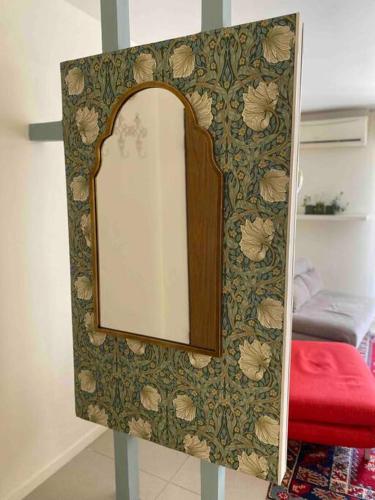 a mirror with a wooden frame on a wall at Beautiful, Central Emek Refaim Home in Yerushalayim