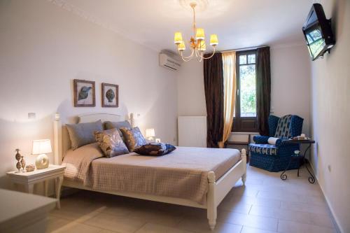 a bedroom with a bed and a tv and a chair at Villa Alyko in Aliko Beach
