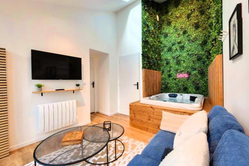 a living room with a blue couch and a tv at Entre Parenthèse in Lion-sur-Mer