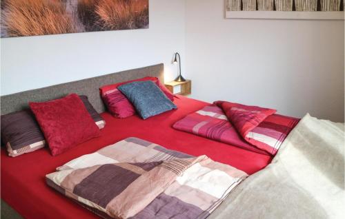 Una cama con sábanas rojas y almohadas coloridas. en Lovely Apartment In Graal Müritz, en Graal-Müritz