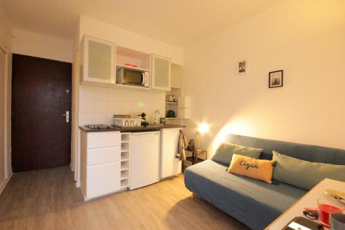 un salon avec un canapé bleu et une cuisine dans l'établissement Studio Maurepas centre-ville, à Maurepas