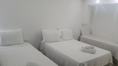 a room with two beds with white sheets at Pousada Suítes do Lago in Capitólio
