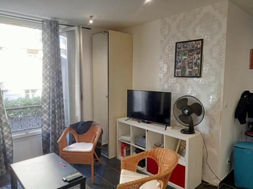 un salon avec une télévision, une table et des chaises dans l'établissement Cosy Studio La Defense, à Puteaux