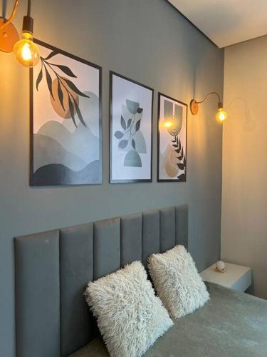 a bedroom with three pictures on the wall and two pillows at Apartamento no centro de Uberlândia in Uberlândia