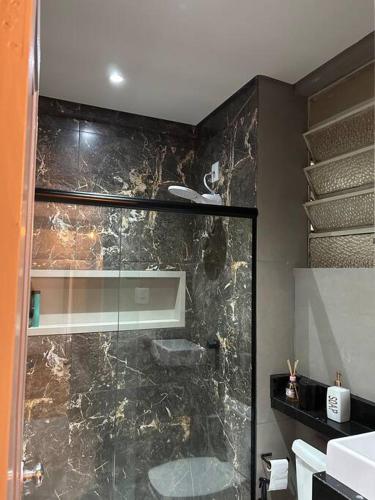 a bathroom with a shower with a stone wall at Apartamento no centro de Uberlândia in Uberlândia